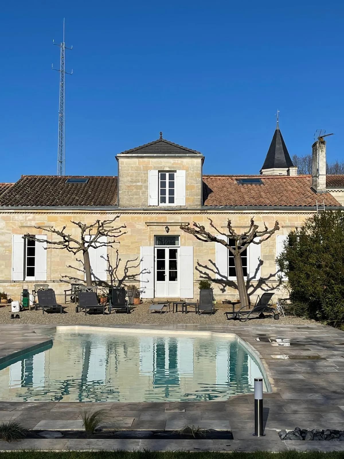 Maison de maître en pierre et sa toiture tuile ravivée vue depuis le jardin à Margaux